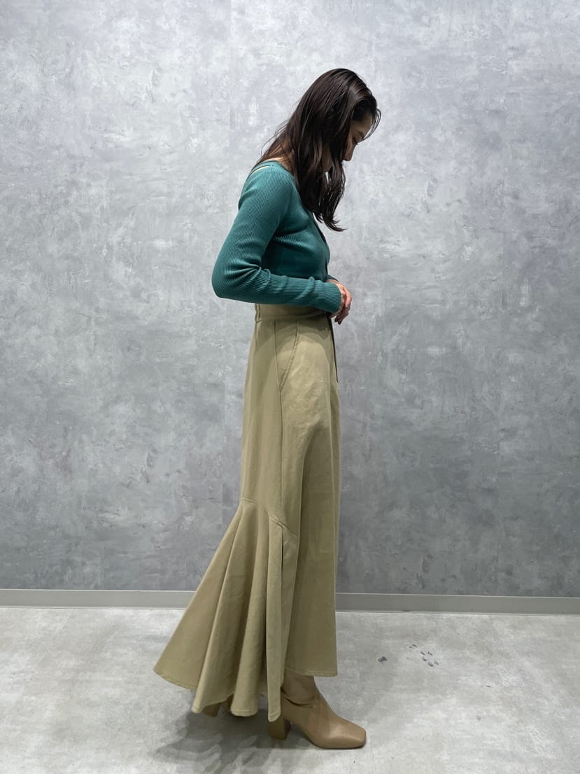 ベージュ系のスカート、ベージュ系のブーツ、グリーン系のニット/セーターを着用したレディースの夏コーディネートの6枚目の写真
