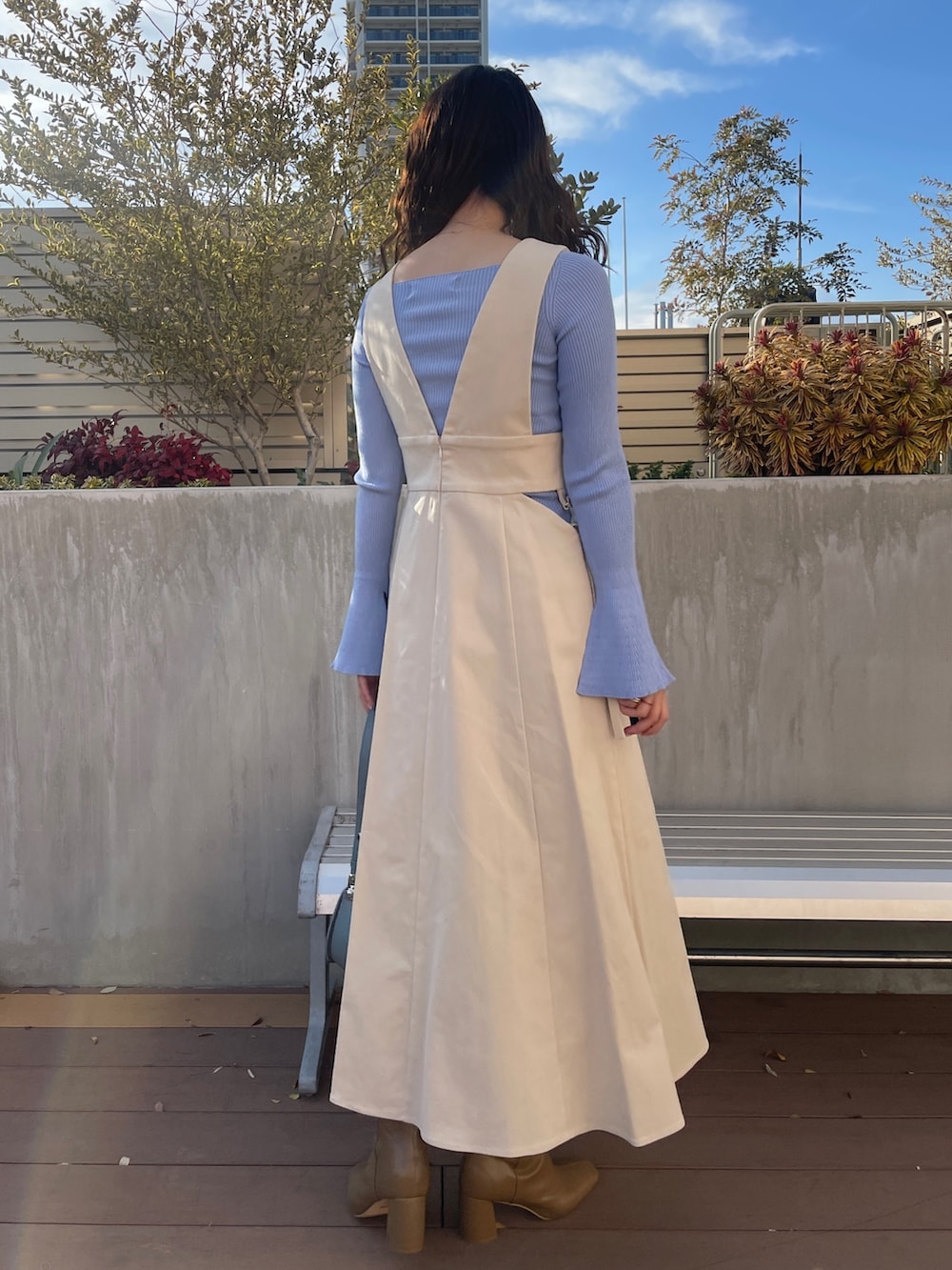 ブルー系のニット/セーター、ベージュ系のブーツ、ホワイト系のジャンパースカートを着用したレディースの冬コーディネートの6枚目の写真