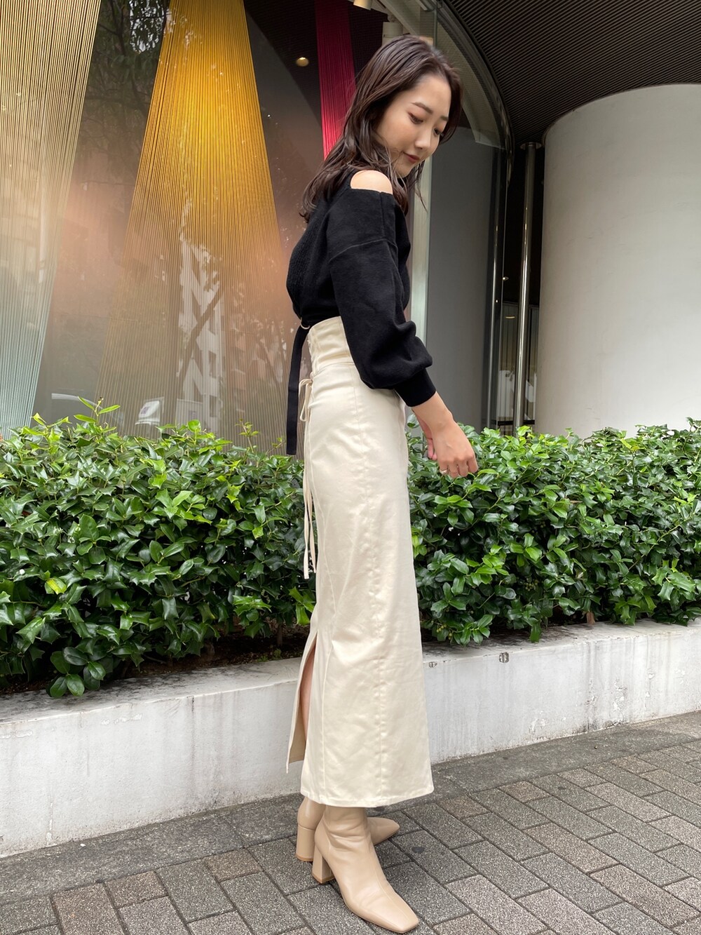 ベージュ系のブーツ、ブラック系のニット/セーター、ホワイト系のスカートを着用したレディースの秋コーディネートの4枚目の写真