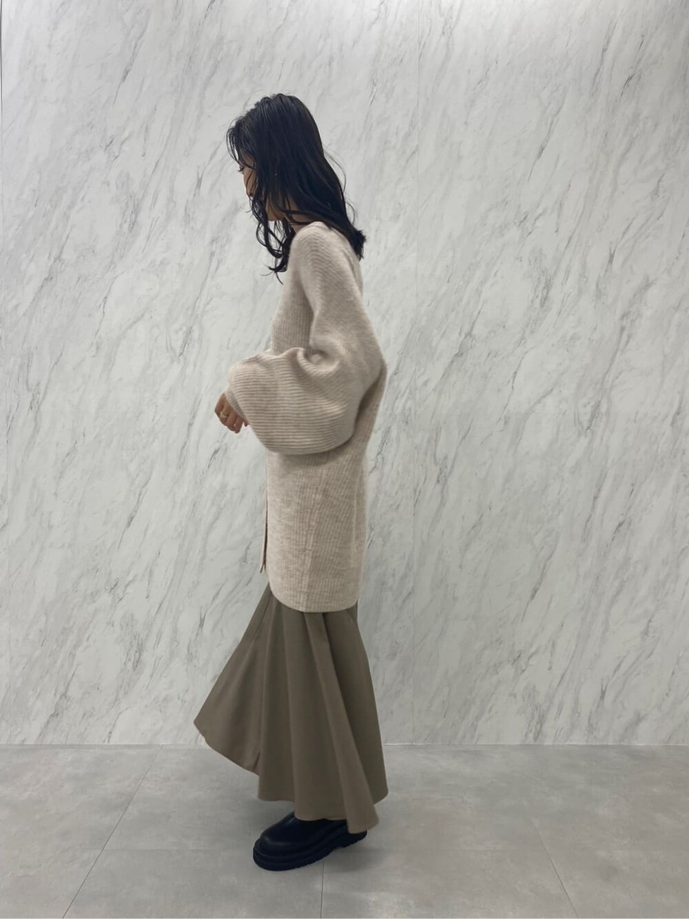ブラック系のブーツ、ベージュ系のスカート、ホワイト系のカーディガン/ボレロを着用したレディースの秋コーディネートの6枚目の写真