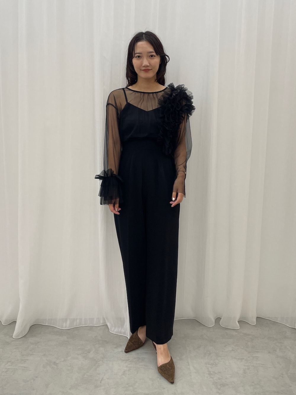 ブラック系のパンツドレス、その他のパンプスを着用したレディースの秋コーディネートの2枚目の写真