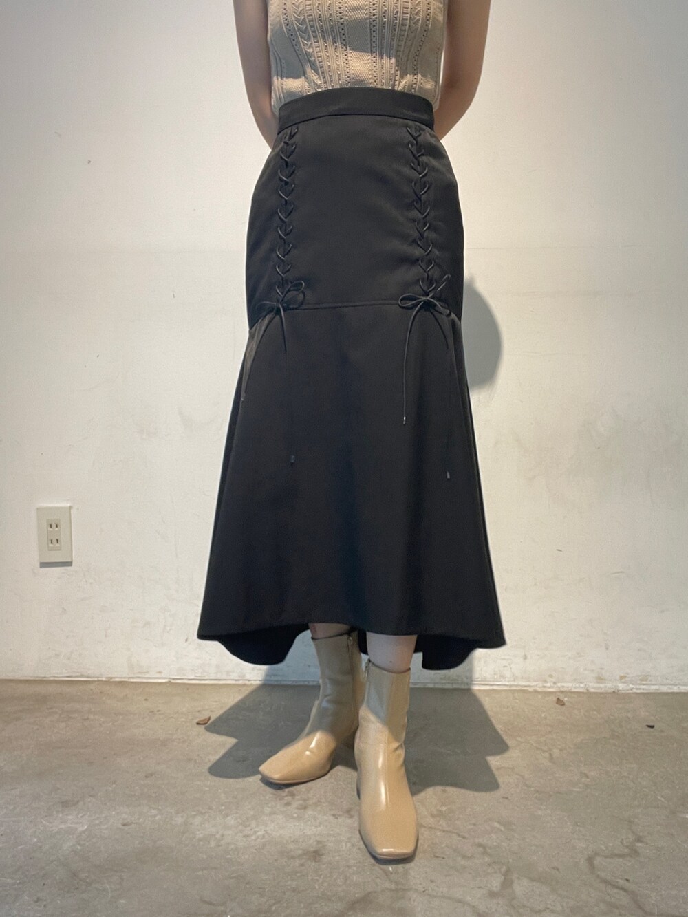 ベージュ系のニット/セーター、ベージュ系のブーツ、ブラック系のスカートを着用したレディースの夏コーディネートの8枚目の写真