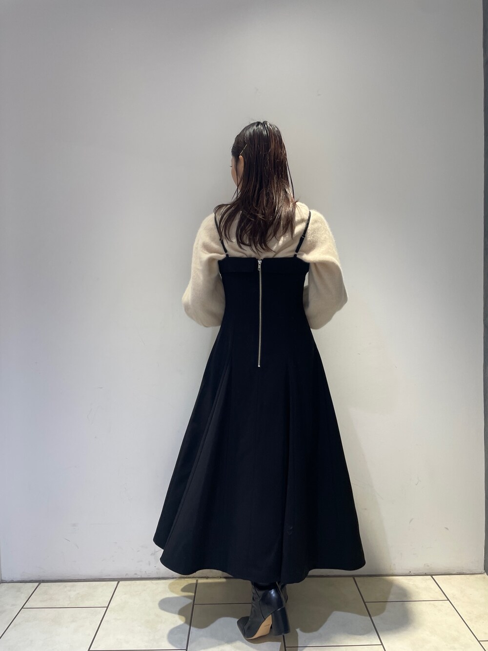 ホワイト系のニット/セーター、ブラック系のワンピース、ブラック系のブーツを着用したレディースの秋コーディネートの6枚目の写真