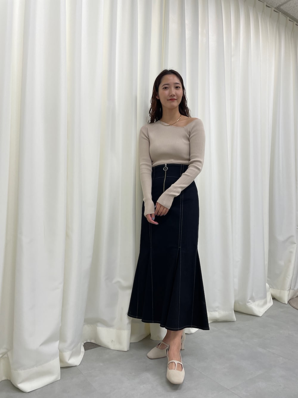 ブラック系のスカート、ベージュ系のニット/セーター、ホワイト系のパンプスを着用したレディースの冬コーディネートの5枚目の写真