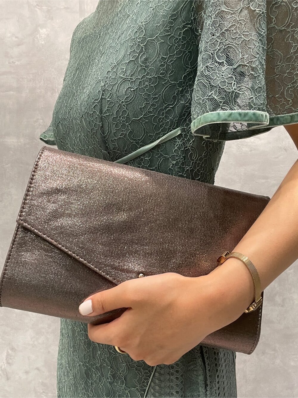 シルバー系のパンプス、シルバー系のクラッチバッグ、グリーン系のドレスを着用したレディースの夏コーディネートの10枚目の写真