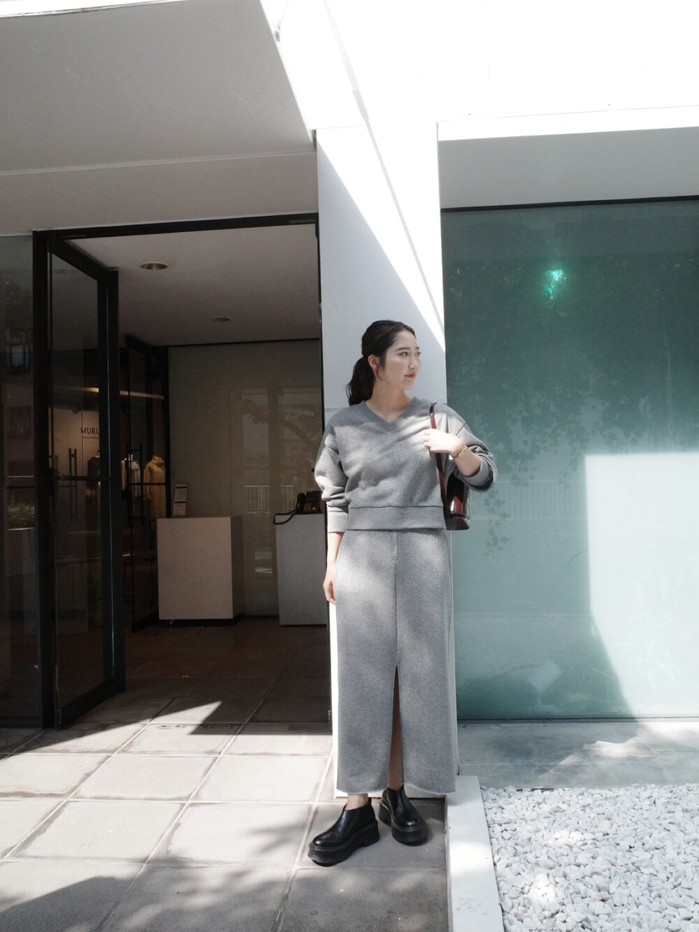 グレー系のスカート、グレー系のスウェット、ブラック系のブーツを着用したレディースの夏コーディネートの3枚目の写真