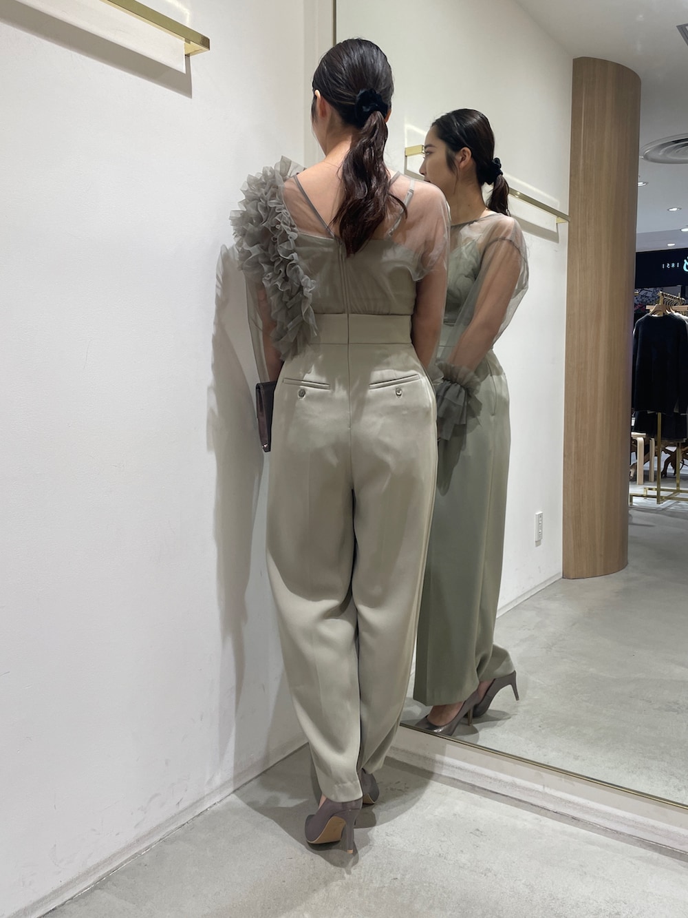 グリーン系のパンツドレス、シルバー系のハンドバッグ、シルバー系のパンプスを着用したレディースの冬コーディネートの6枚目の写真