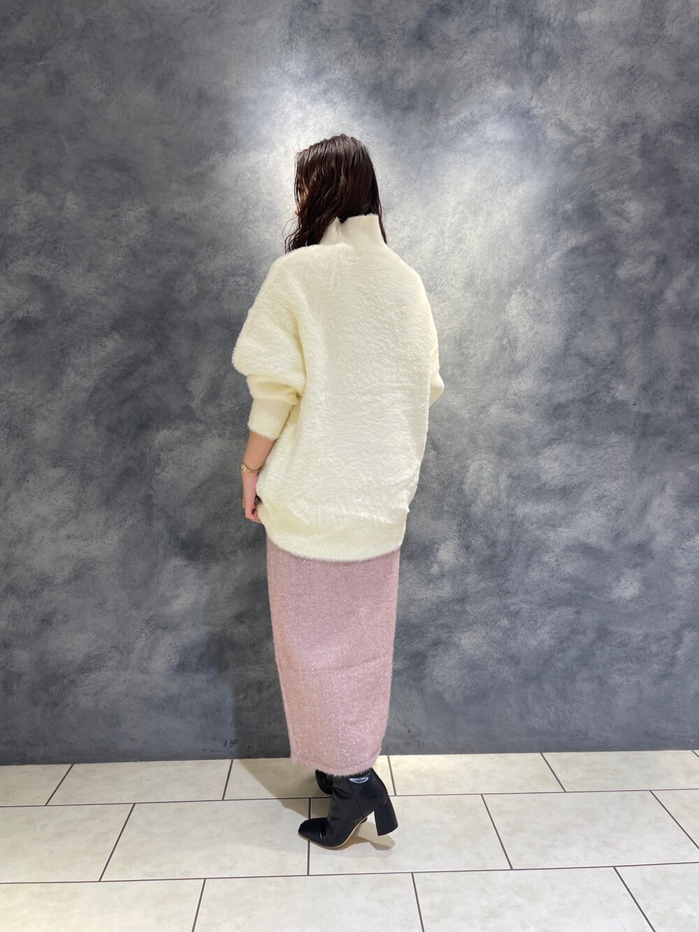 ホワイト系のニット/セーター、ピンク系のスカート、ブラック系のブーツを着用したレディースの秋コーディネートの6枚目の写真