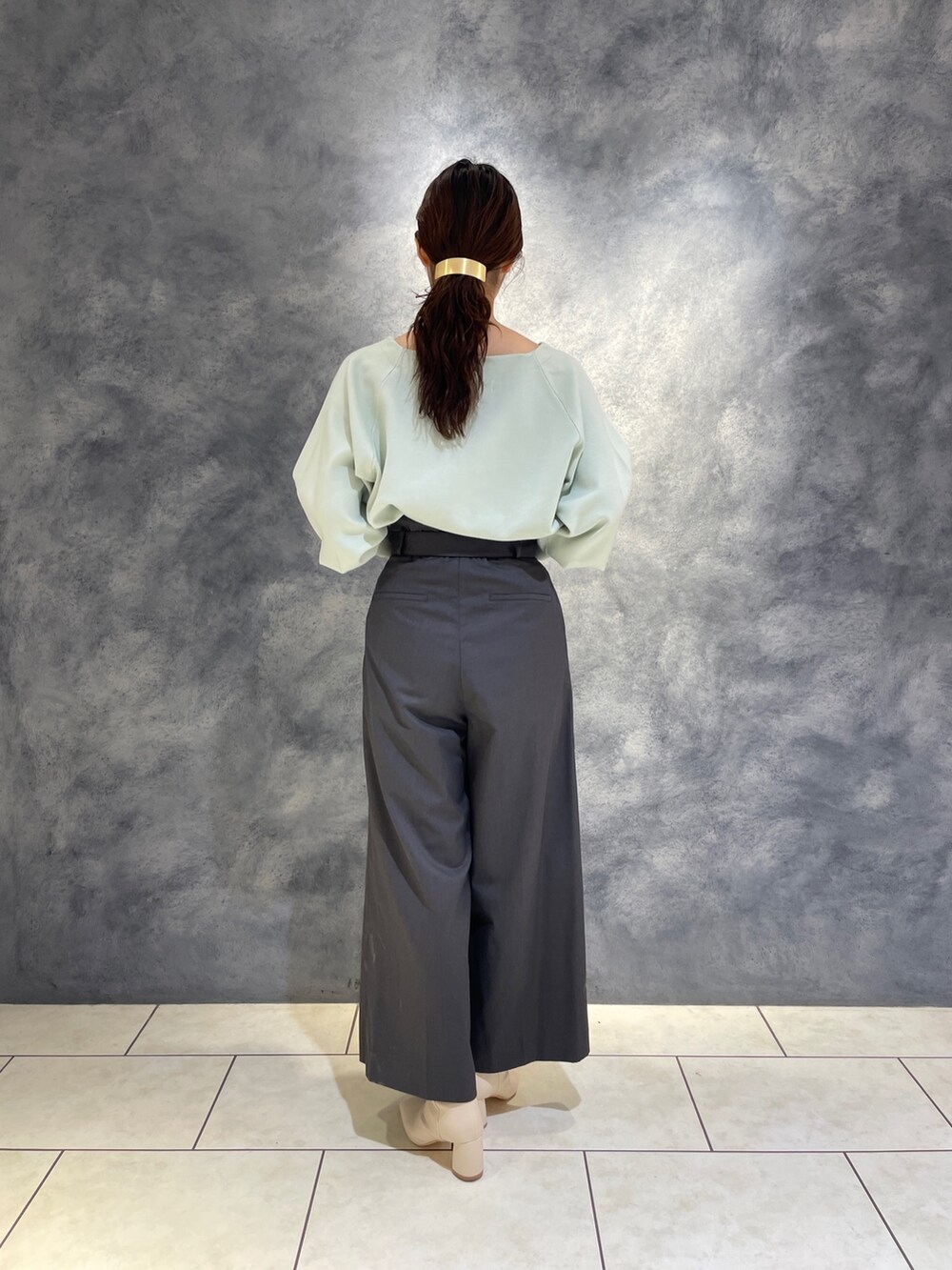 グレー系のその他パンツ、ホワイト系のブーツ、グリーン系のニット/セーターを着用したレディースの冬コーディネートの6枚目の写真