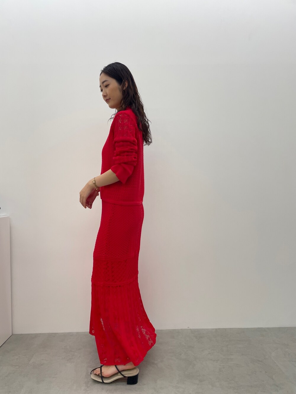 レッド系のカーディガン/ボレロ、レッド系のスカート、ブラック系のサンダルを着用したレディースの春コーディネートの7枚目の写真