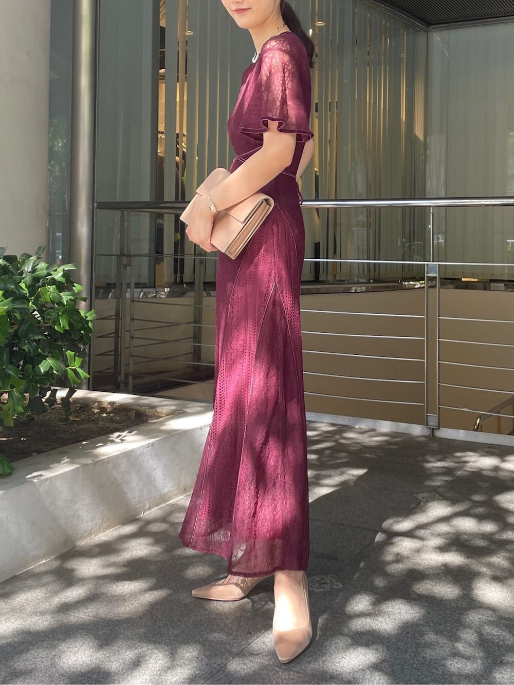 レッド系のドレス、ゴールド系のクラッチバッグ、ゴールド系のパンプスを着用したレディースの秋コーディネートの4枚目の写真