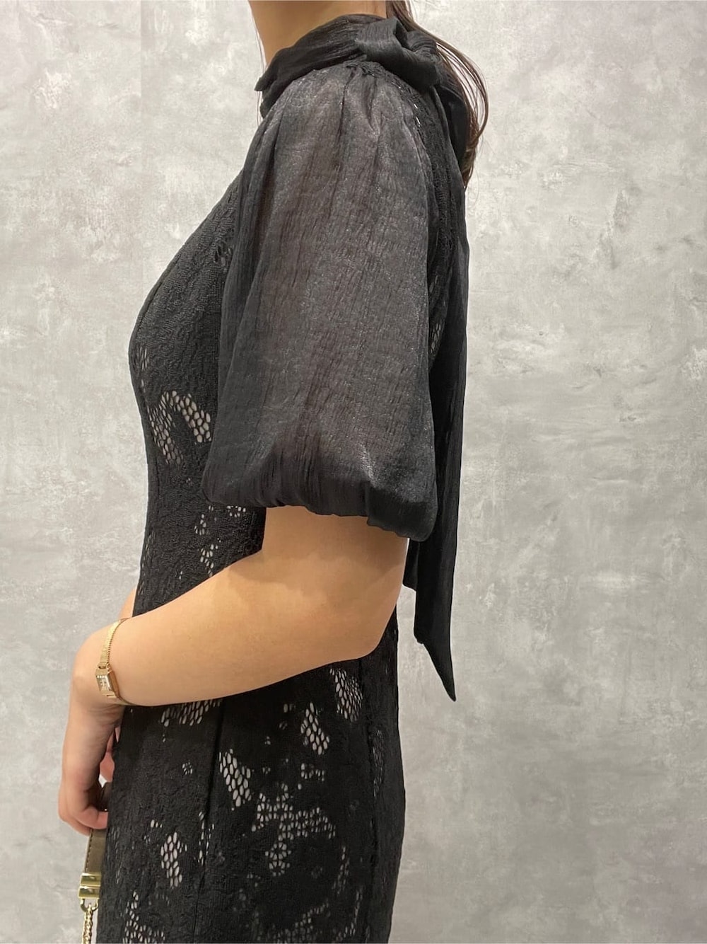 ゴールド系のパンプス、ゴールド系のクラッチバッグ、ブラック系のドレスを着用したレディースの秋コーディネートの8枚目の写真