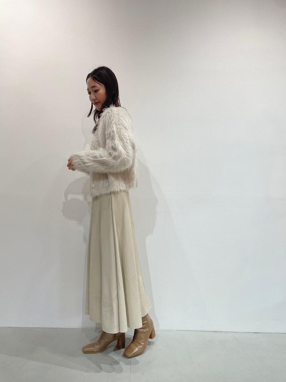 ホワイト系のスカート、ベージュ系のブーツ、オレンジ系のニット/セーターを着用したレディースの夏コーディネートの5枚目の写真