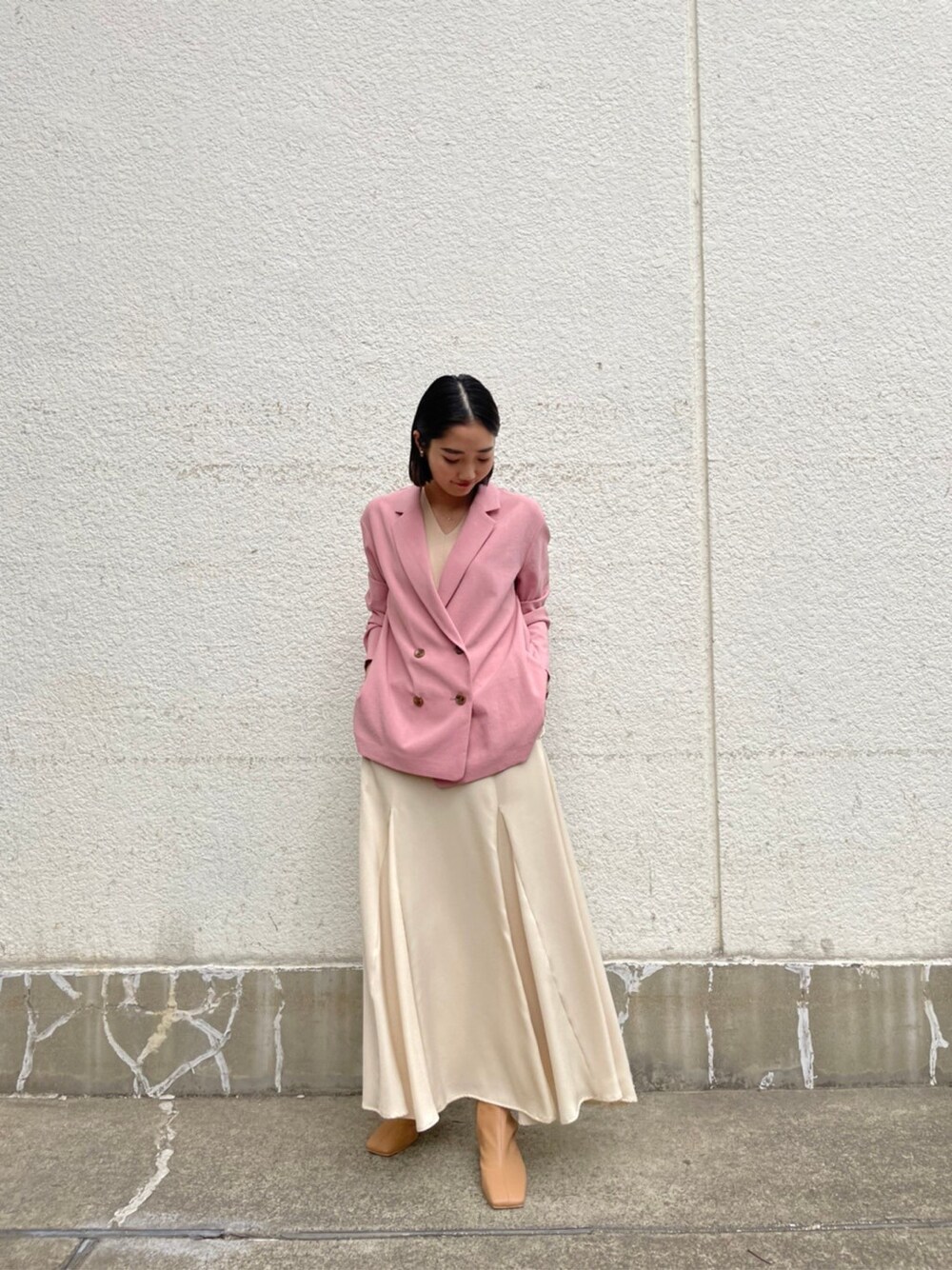 ホワイト系のスカート、ベージュ系のブーツ、ピンク系のテーラードジャケットを着用したレディースの春コーディネートの6枚目の写真