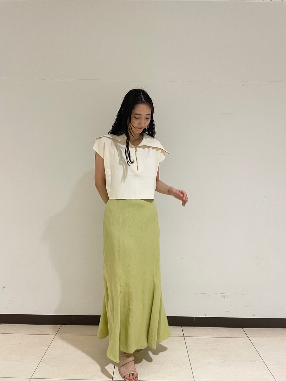 ホワイト系のニット/セーター、ベージュ系のサンダル、グリーン系のスカートを着用したレディースの春コーディネートの4枚目の写真