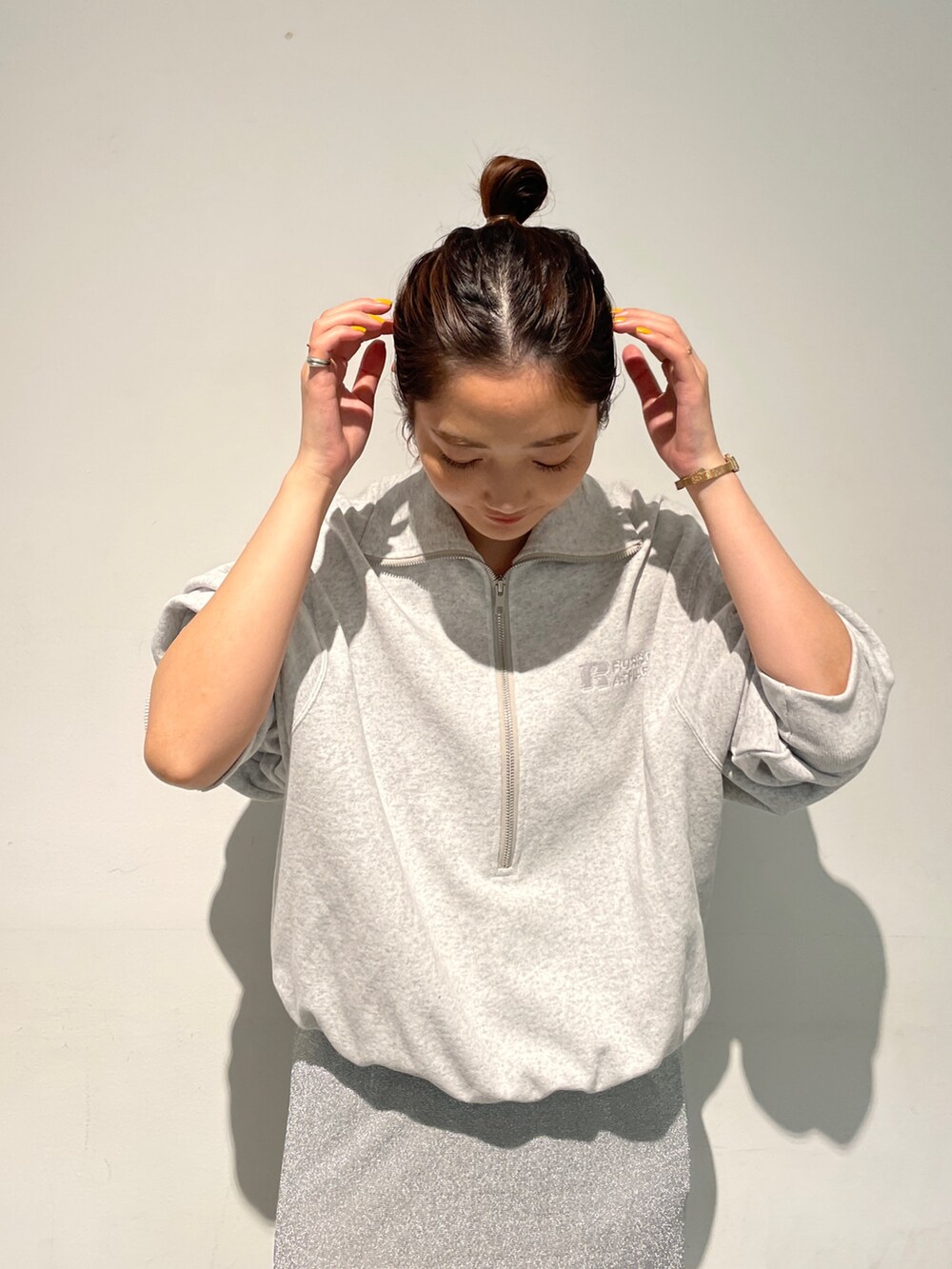 シルバー系のスカート、グレー系のスウェット、ホワイト系のスニーカーを着用したレディースの秋コーディネートの6枚目の写真