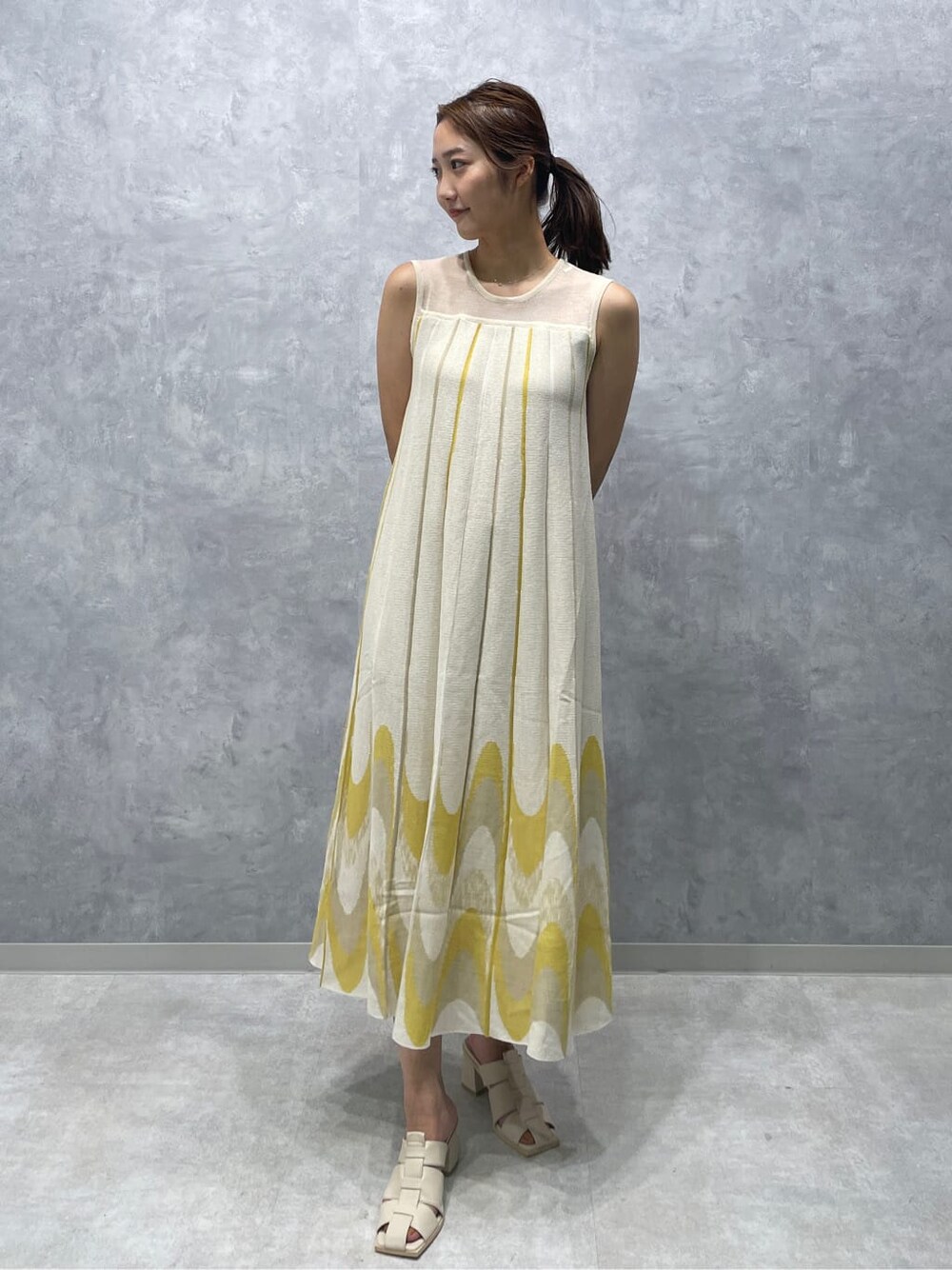 ホワイト系のサンダル、イエロー系のワンピースを着用したレディースの夏コーディネートの2枚目の写真