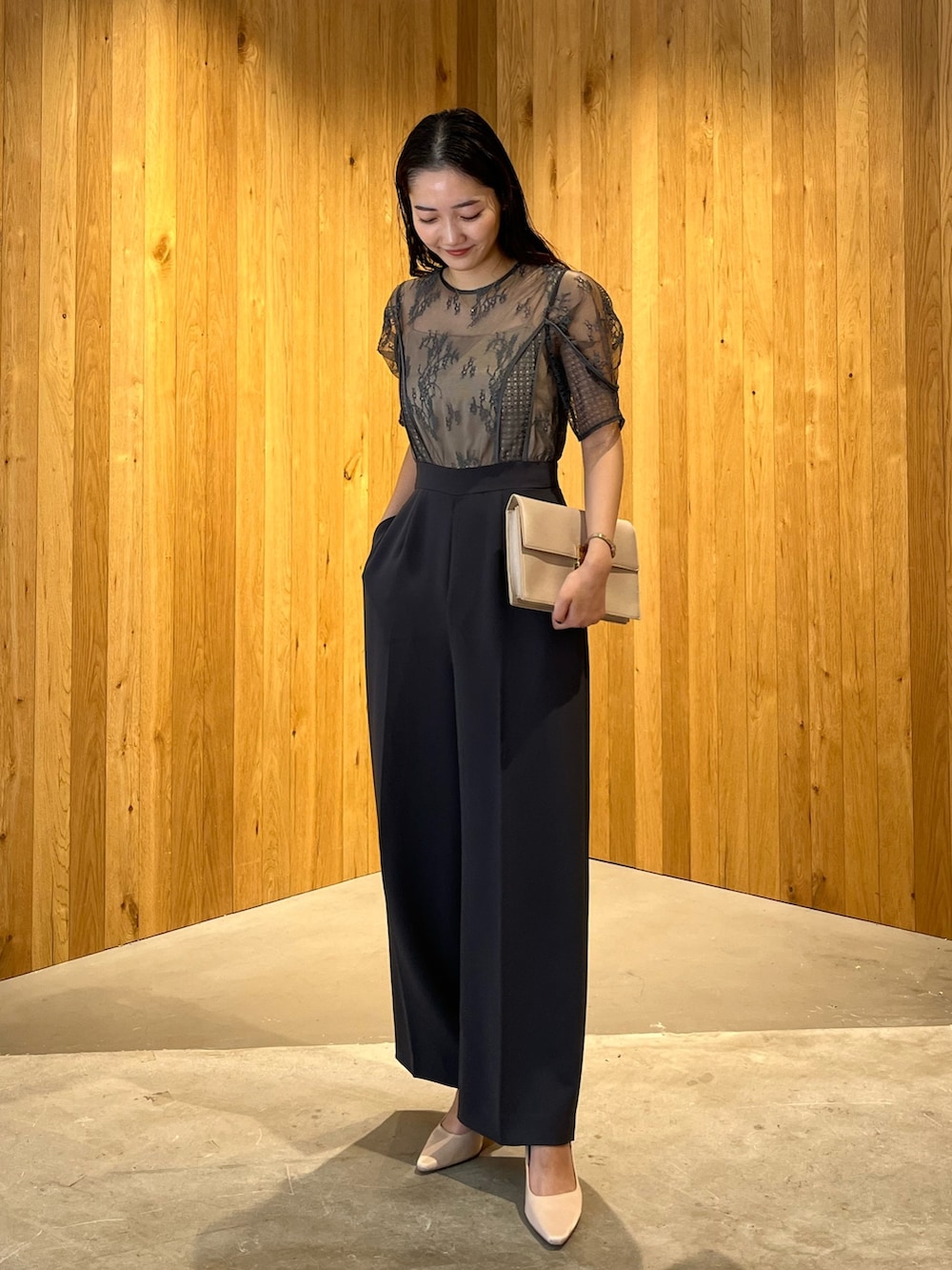 グレー系のパンツドレス、ベージュ系のクラッチバッグ、ベージュ系のパンプスを着用したレディースの冬コーディネートの2枚目の写真