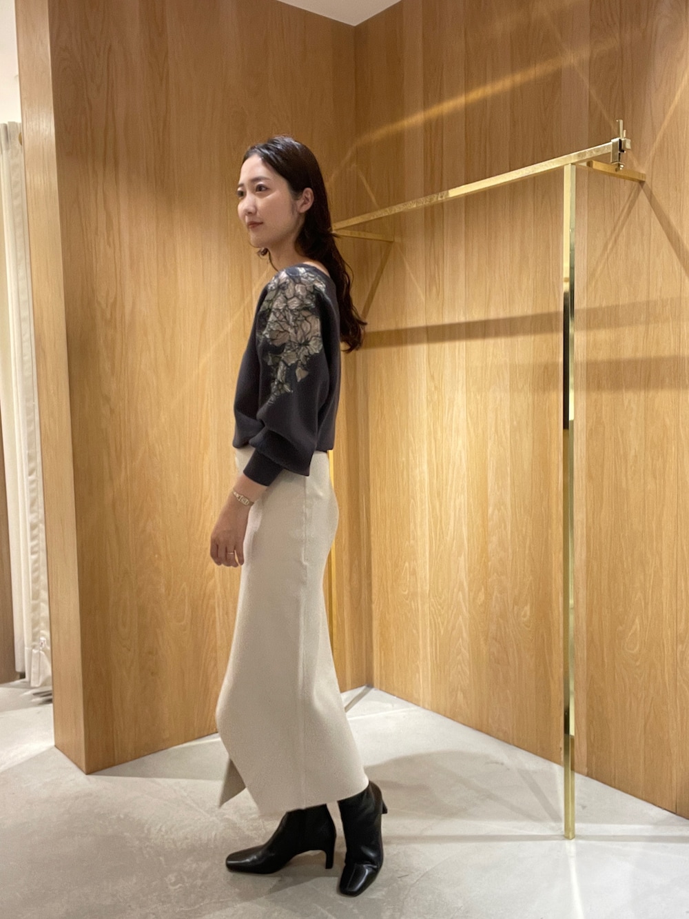 ホワイト系のスカート、グレー系のニット/セーター、ブラック系のブーツを着用したレディースの秋コーディネートの3枚目の写真