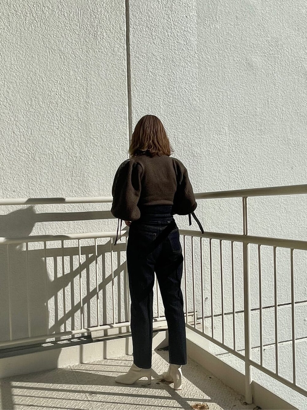 ホワイト系のその他シューズ、ブラウン系のニット/セーター、ブルー系のデニムパンツを着用したレディースの冬コーディネートの4枚目の写真