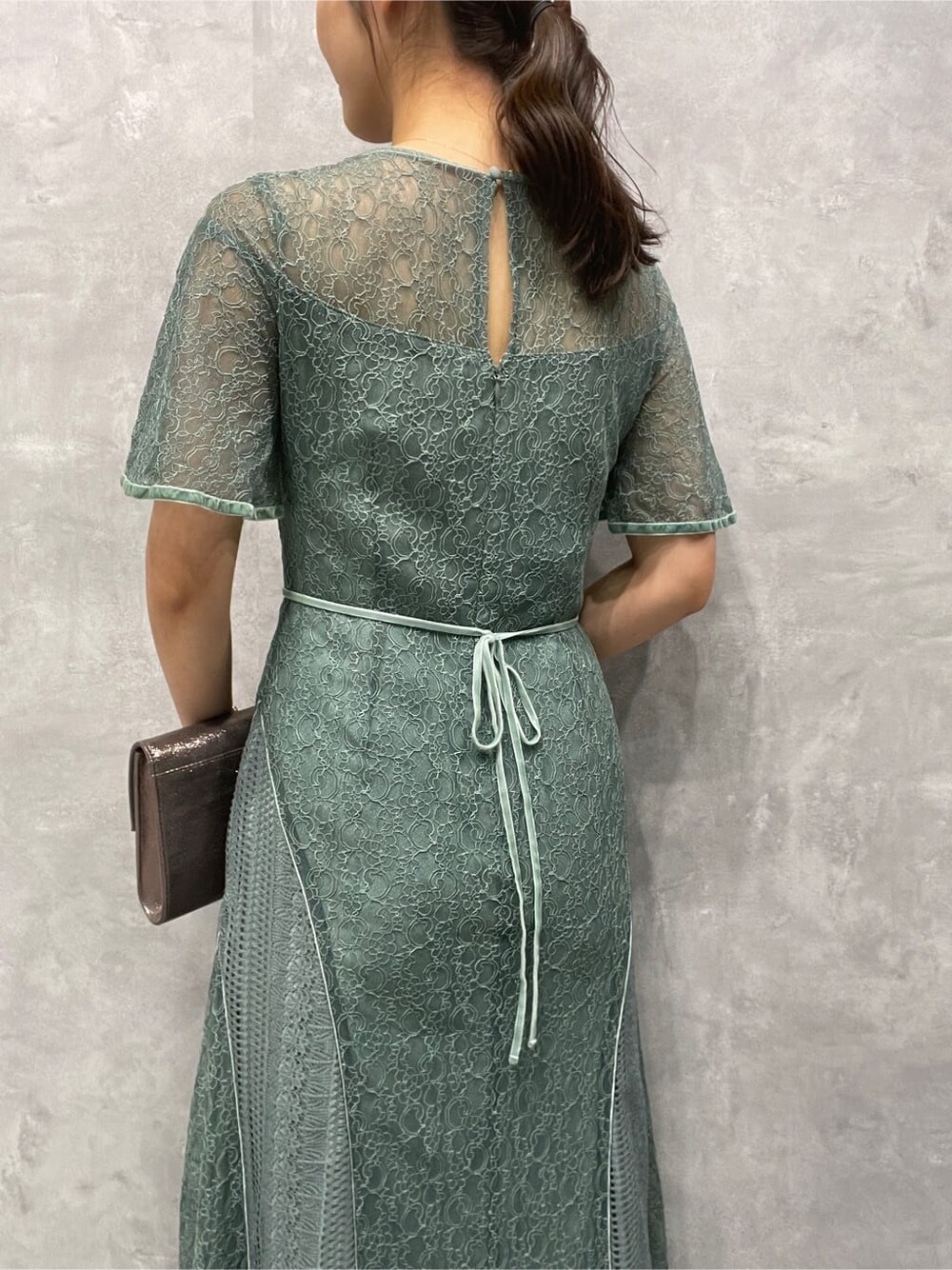 シルバー系のパンプス、シルバー系のクラッチバッグ、グリーン系のドレスを着用したレディースの夏コーディネートの9枚目の写真