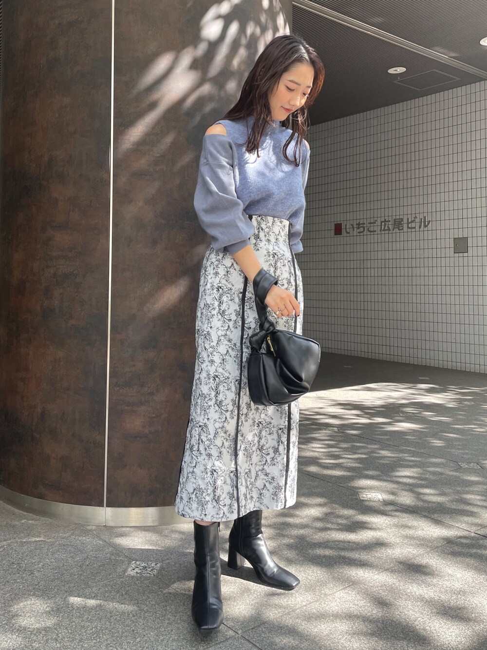 ブラック系のハンドバッグ、ブラック系のスカート、ブラック系のブーツを着用したレディースの秋コーディネートの4枚目の写真