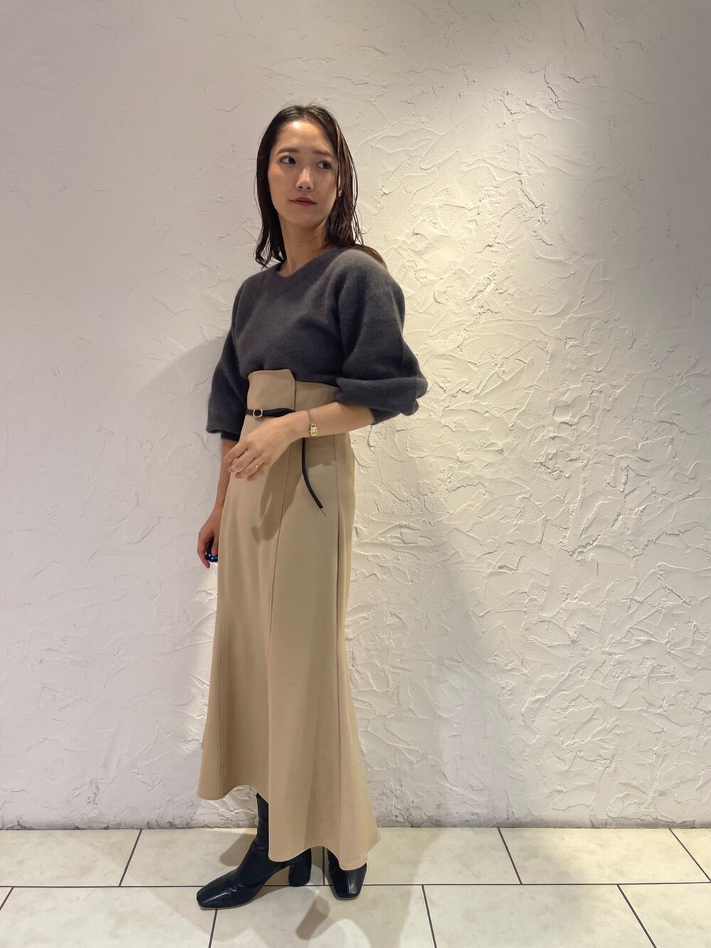 グレー系のニット/セーター、ベージュ系のスカート、ブラック系のブーツを着用したレディースの秋コーディネートの4枚目の写真