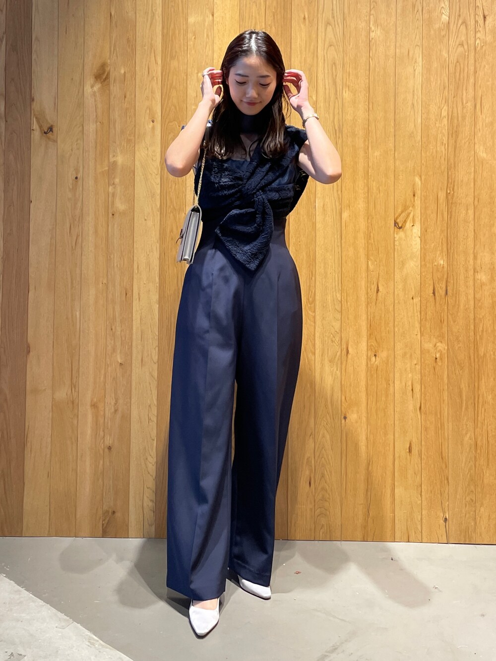 グレー系のクラッチバッグ、グレー系のパンプス、ブルー系のパンツドレスを着用したレディースの冬コーディネートの3枚目の写真