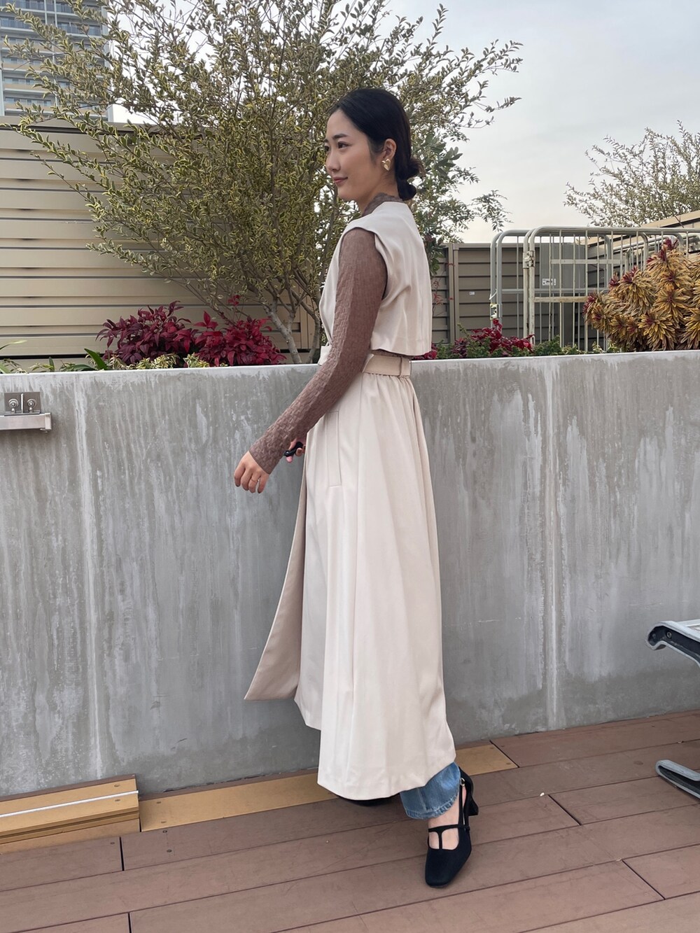 ホワイト系のトレンチコート、ブルー系のデニムパンツ、ブラック系のパンプスを着用したレディースの冬コーディネートの3枚目の写真