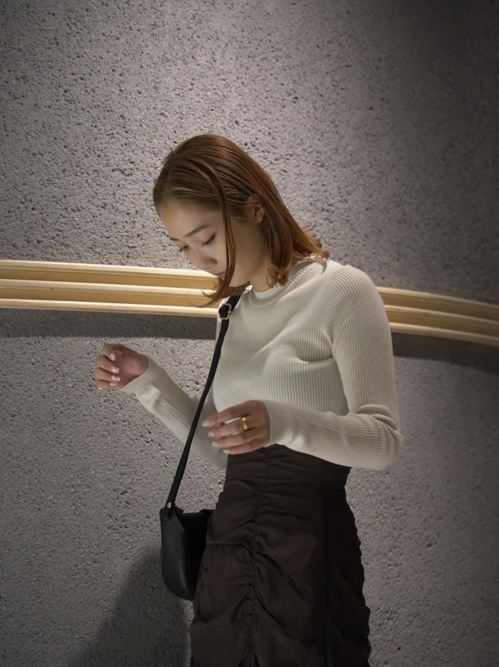 ブラック系のショルダーバッグ、ブラウン系のスカート、ホワイト系のニット/セーターを着用したレディースの秋コーディネートの6枚目の写真