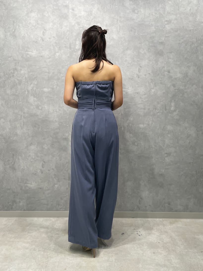 ゴールド系のパンプス、ゴールド系のクラッチバッグ、ブルー系のパンツドレスを着用したレディースの夏コーディネートの6枚目の写真