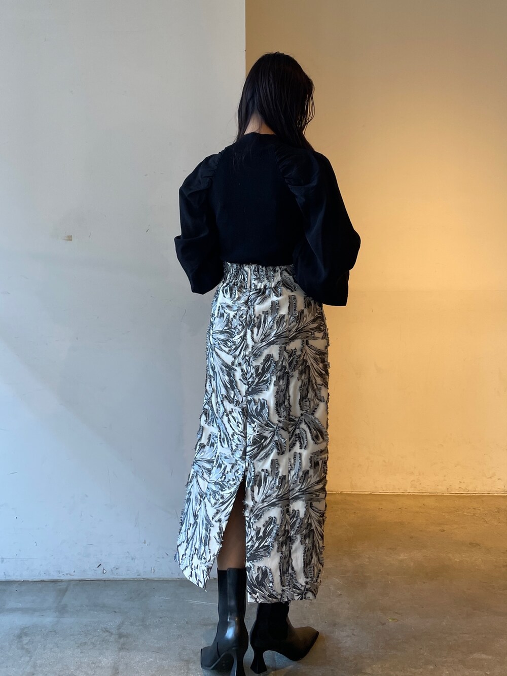 ブラック系のスカート、ブラック系のニット/セーター、ブラック系のブーツを着用したレディースの冬コーディネートの4枚目の写真