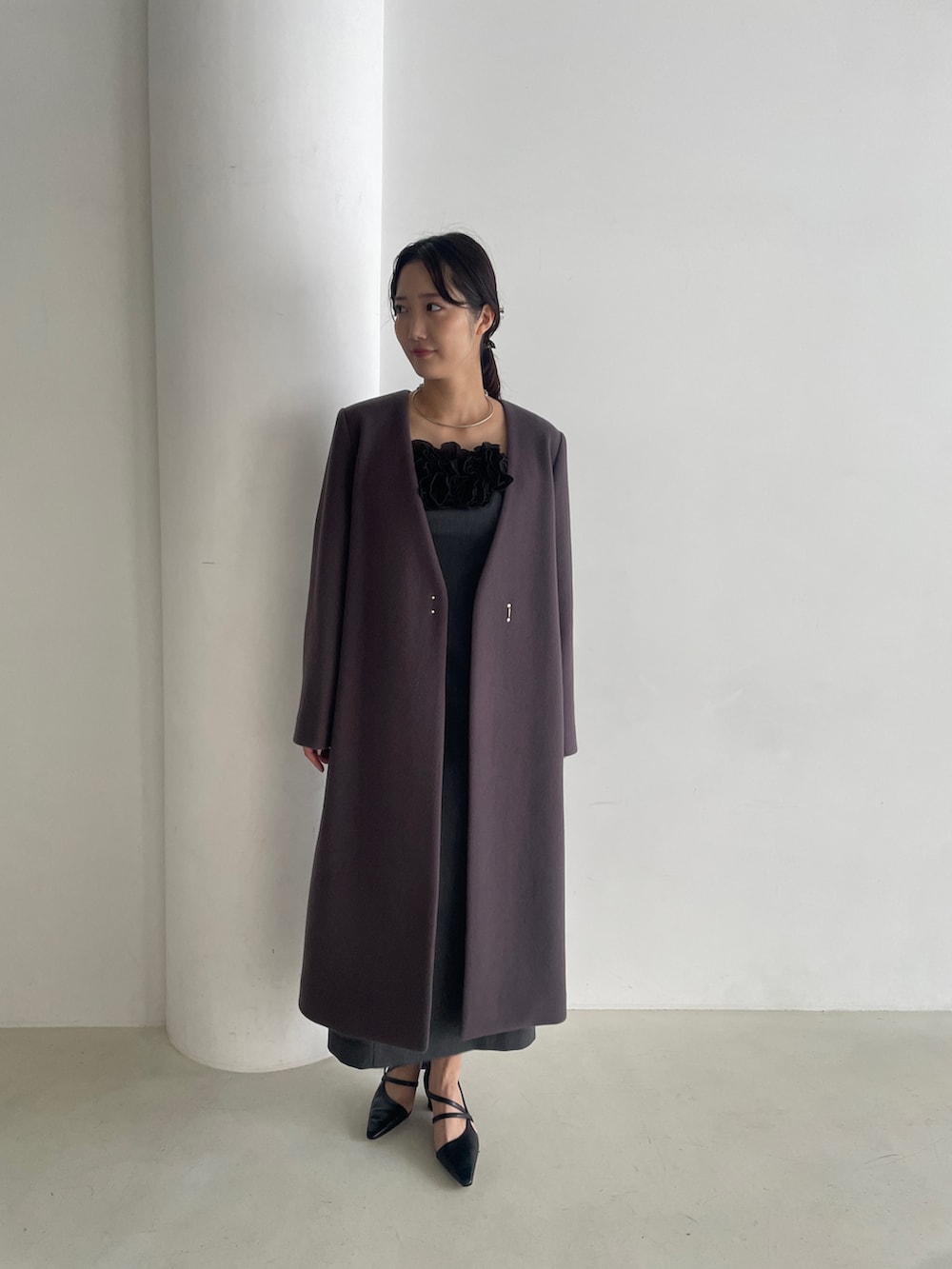 グレー系のドレス、ブラック系のパンプス、グレー系のチェスターコートを着用したレディースの秋コーディネートの4枚目の写真