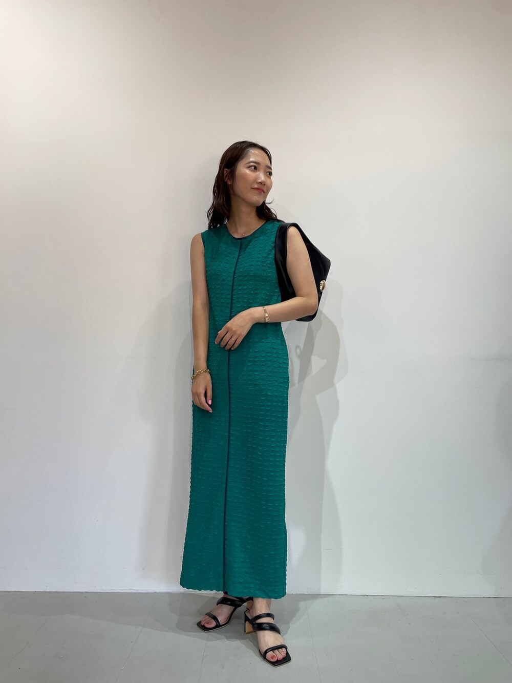 グリーン系のワンピース、ブラック系のサンダル、ブラック系のハンドバッグを着用したレディースの夏コーディネートの4枚目の写真