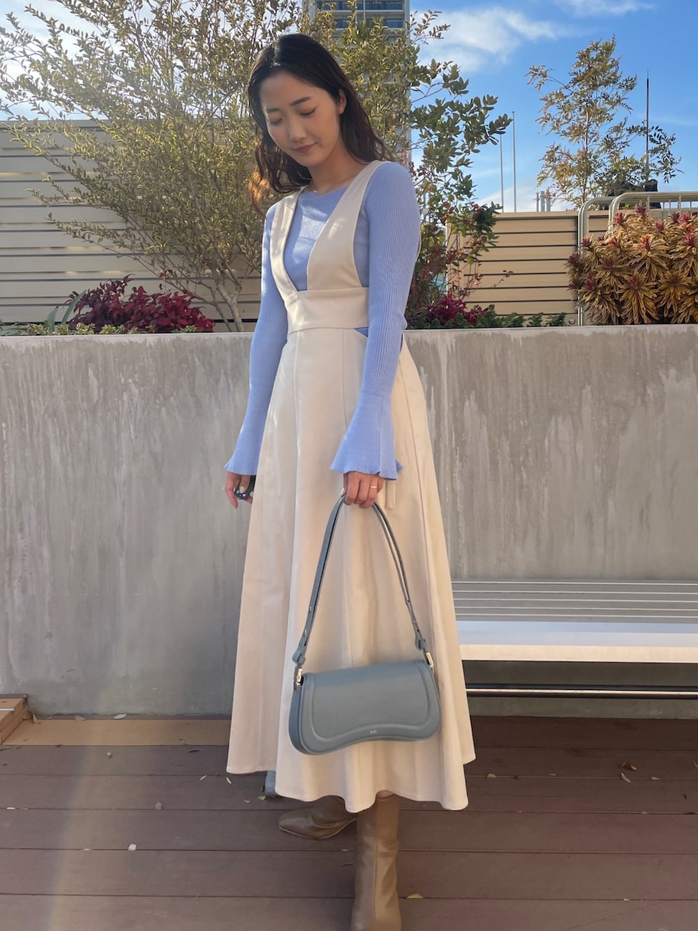 ブルー系のニット/セーター、ベージュ系のブーツ、ホワイト系のジャンパースカートを着用したレディースの冬コーディネートの4枚目の写真