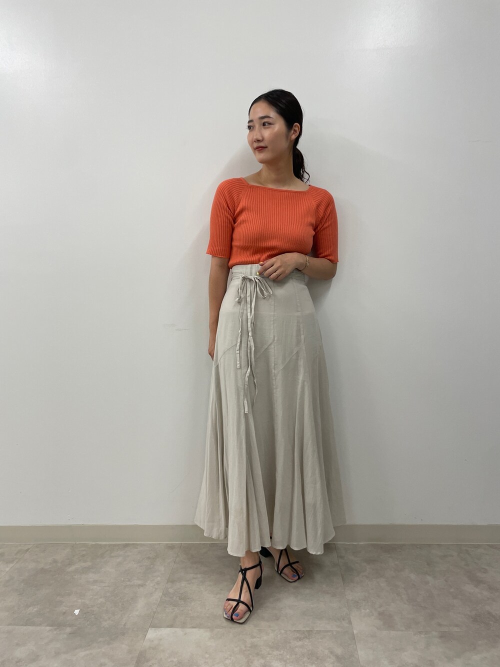 グレー系のスカート、ピンク系のニット/セーター、ブラック系のサンダルを着用したレディースの夏コーディネートの3枚目の写真