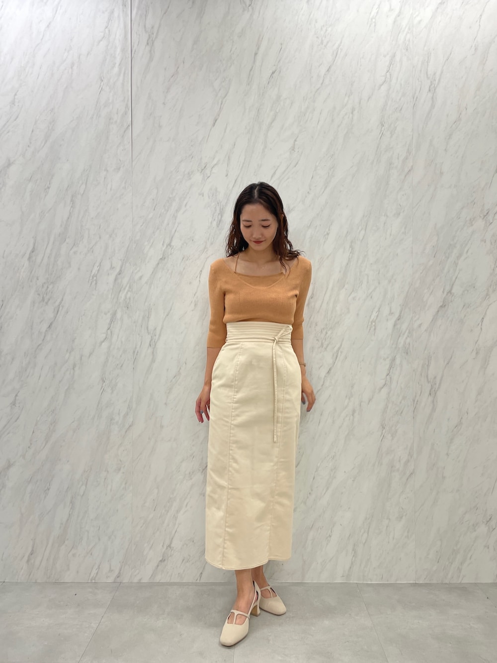 ホワイト系のパンプス、オレンジ系のニット/セーター、ホワイト系のスカートを着用したレディースの冬コーディネートの3枚目の写真