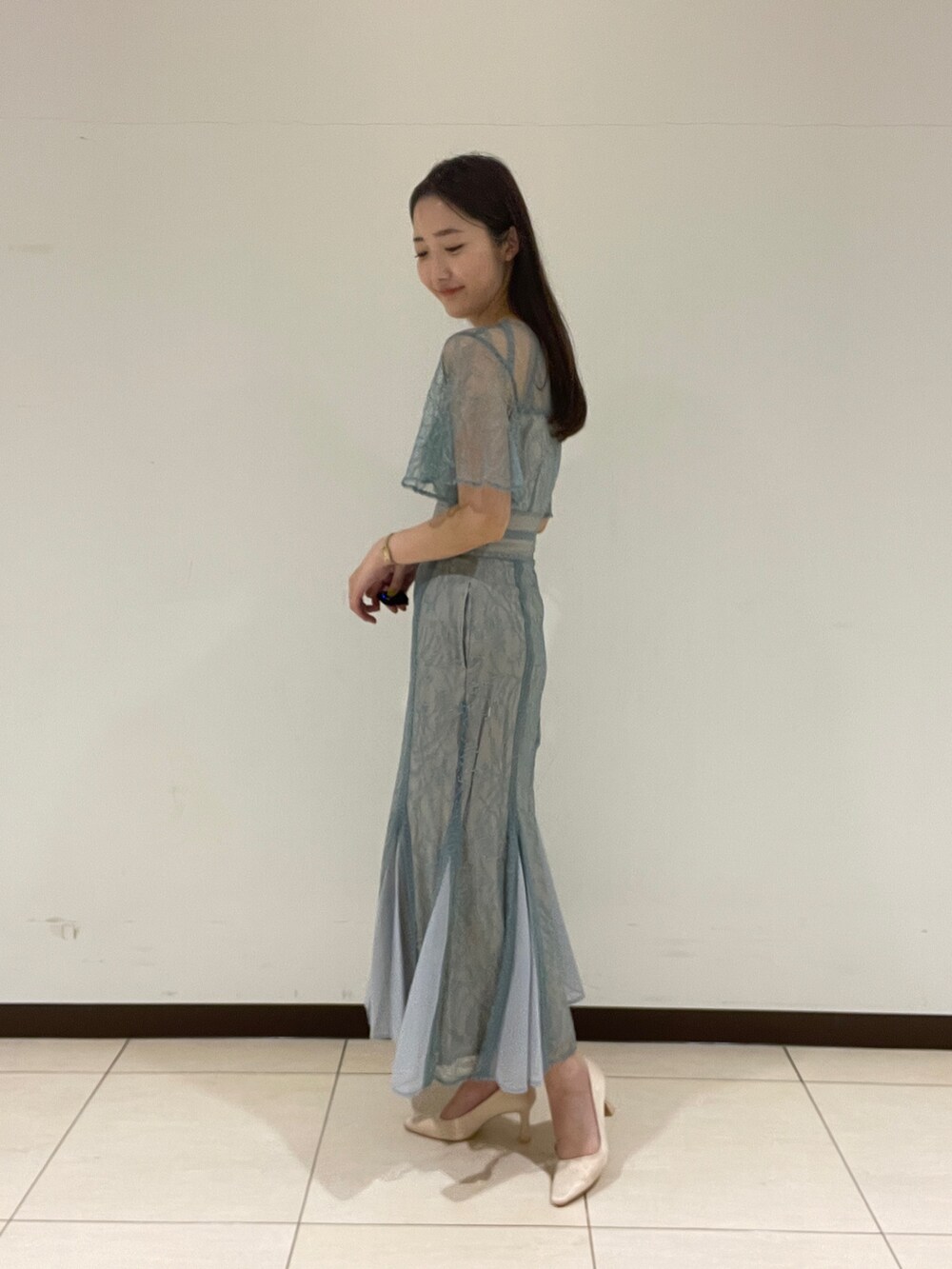 グリーン系のドレス、ベージュ系のパンプスを着用したレディースの春コーディネートの3枚目の写真