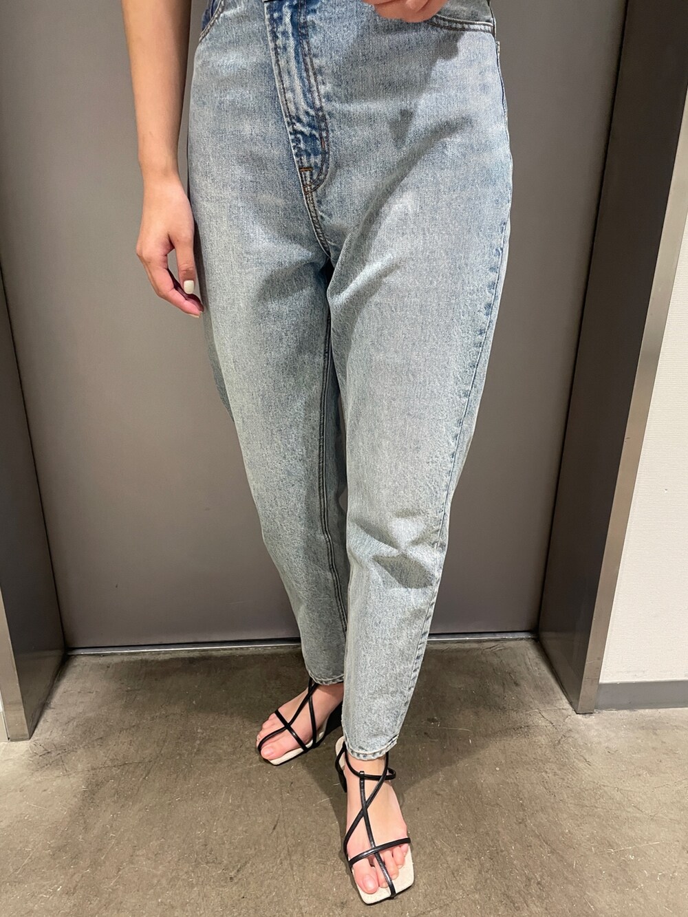 ブルー系のデニムパンツ、ベージュ系のニット/セーター、ブラック系のサンダルを着用したレディースの春コーディネートの7枚目の写真