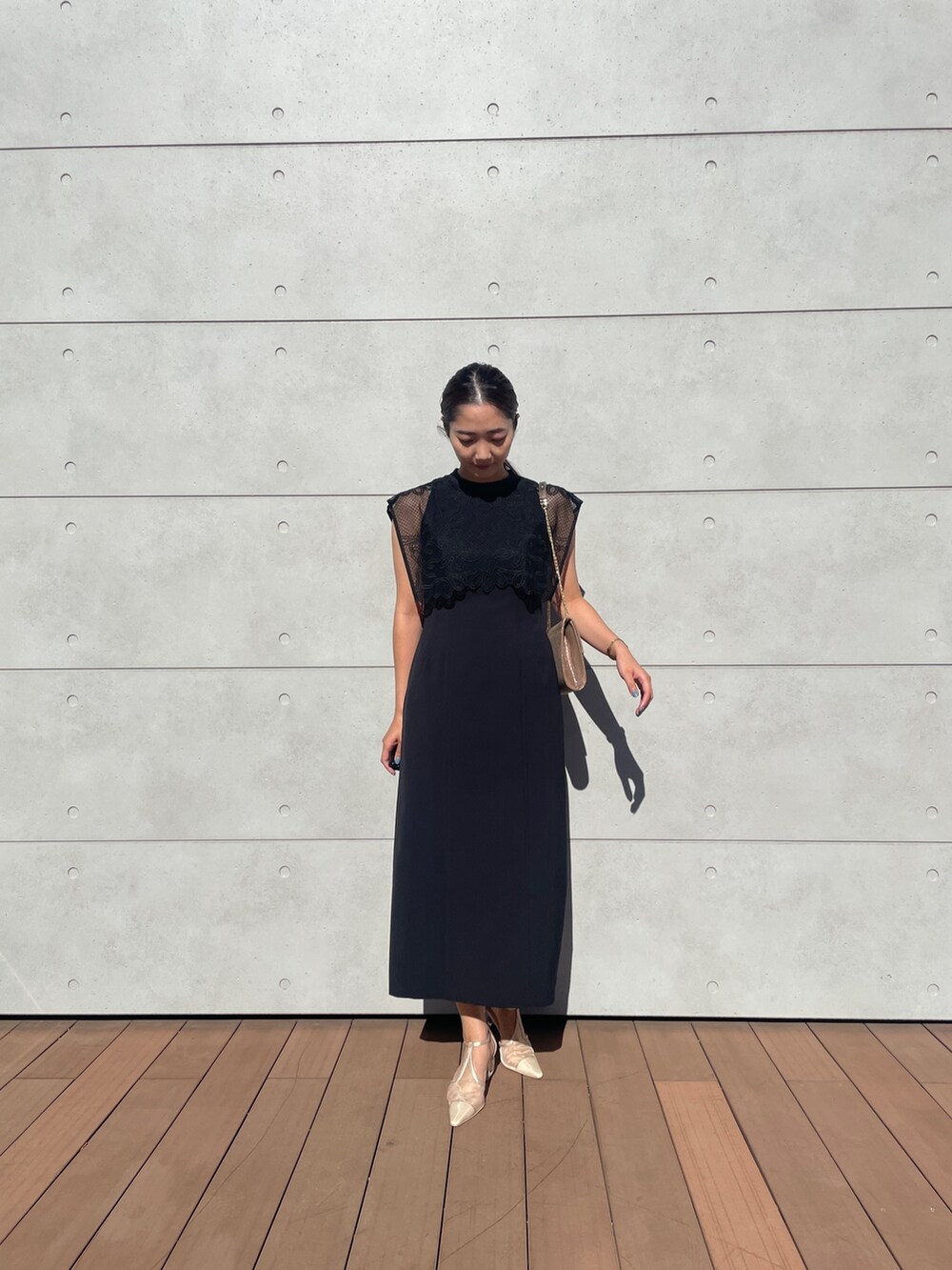 ブラック系のドレス、ベージュ系のパンプス、ゴールド系のハンドバッグを着用したレディースの秋コーディネートの3枚目の写真