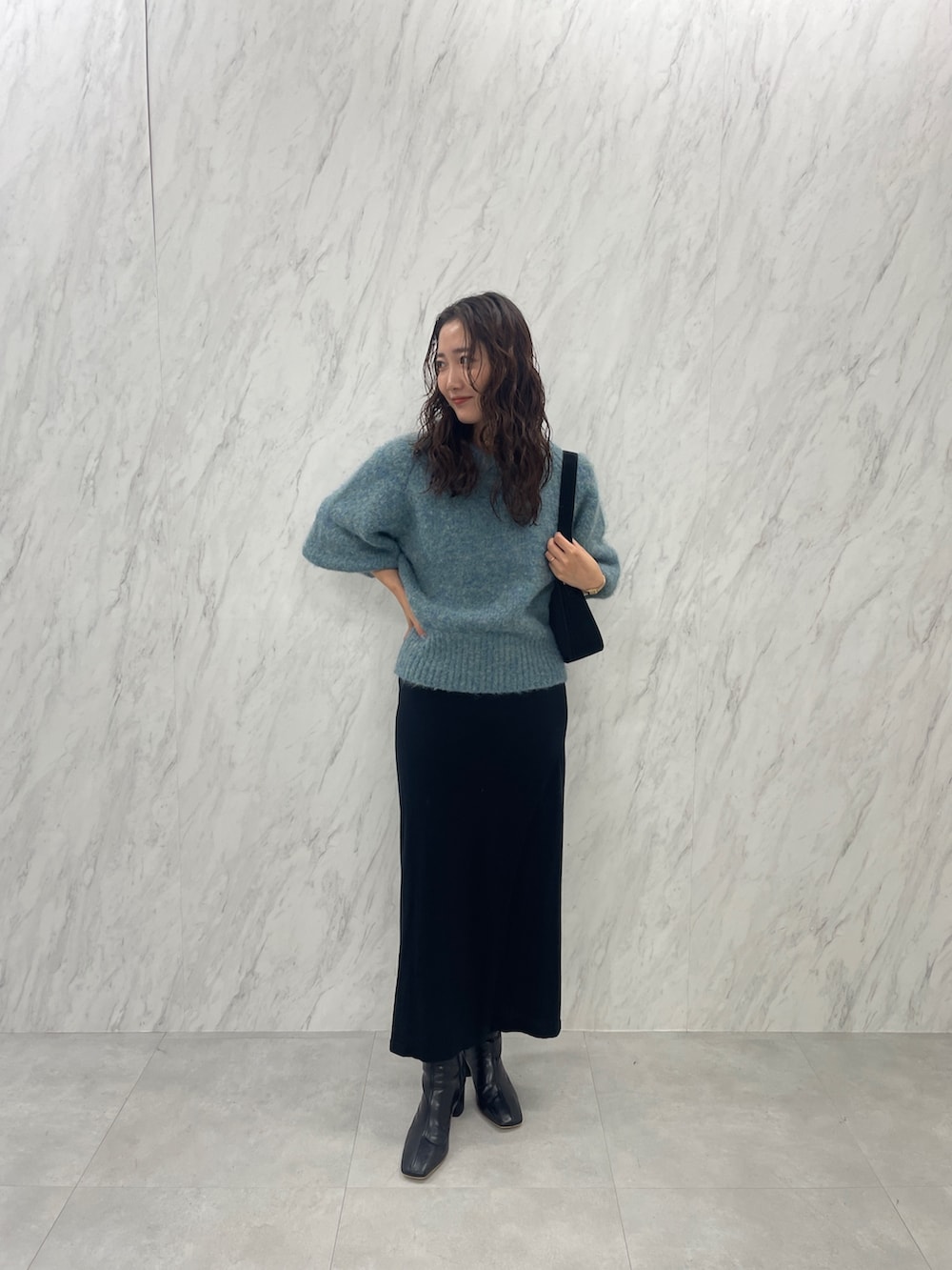 グリーン系のニット/セーター、ブラック系のブーツ、ブラック系のスカートを着用したレディースの冬コーディネートの2枚目の写真