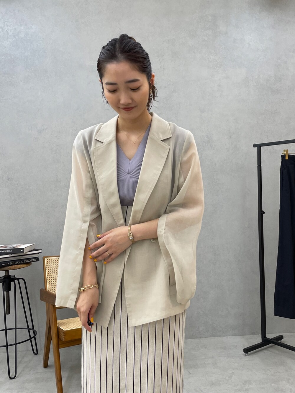 グレー系のスカート、ホワイト系のテーラードジャケット、ブルー系のニット/セーターを着用したレディースの春コーディネートの4枚目の写真