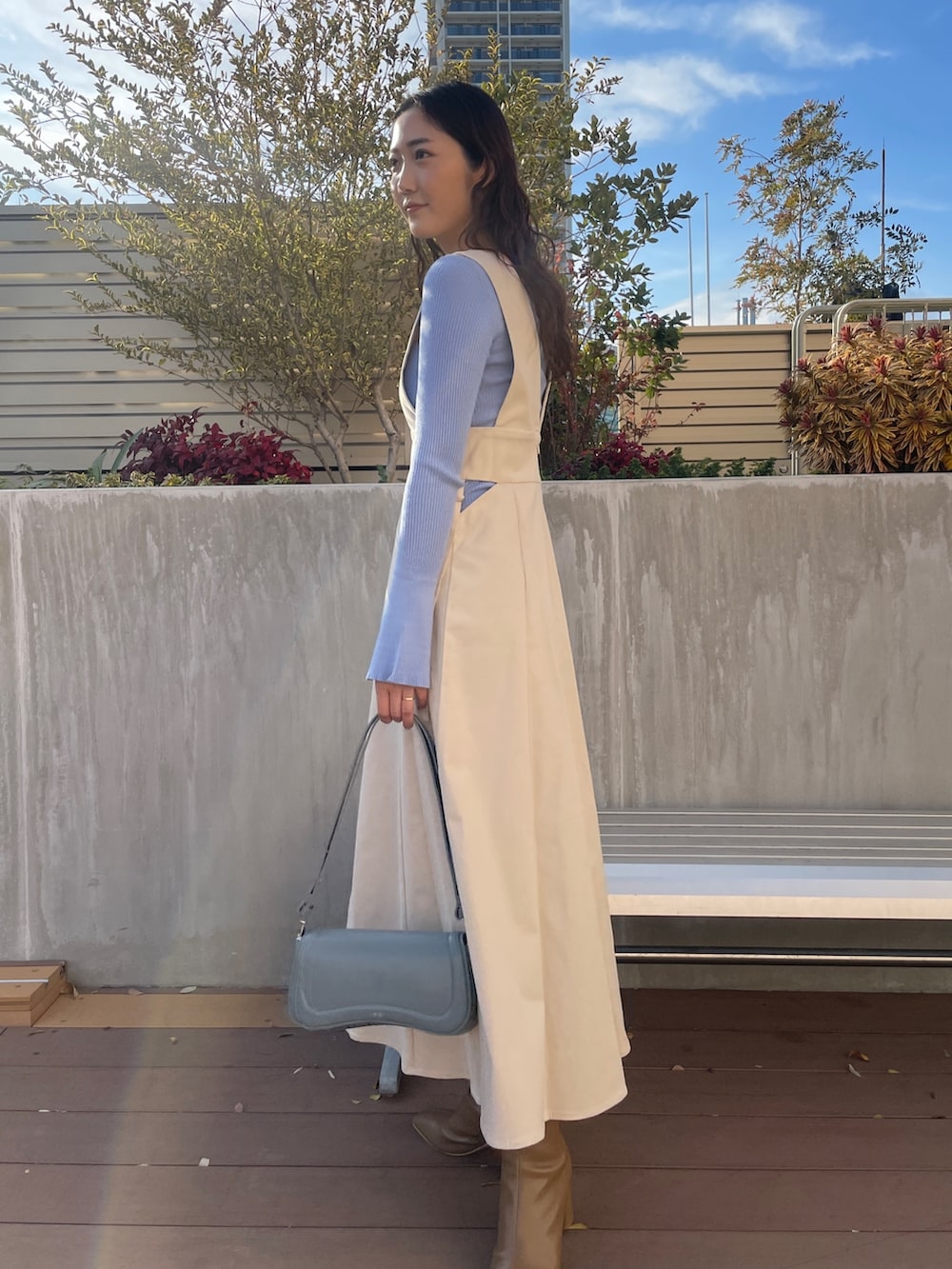 ブルー系のニット/セーター、ベージュ系のブーツ、ホワイト系のジャンパースカートを着用したレディースの冬コーディネートの5枚目の写真