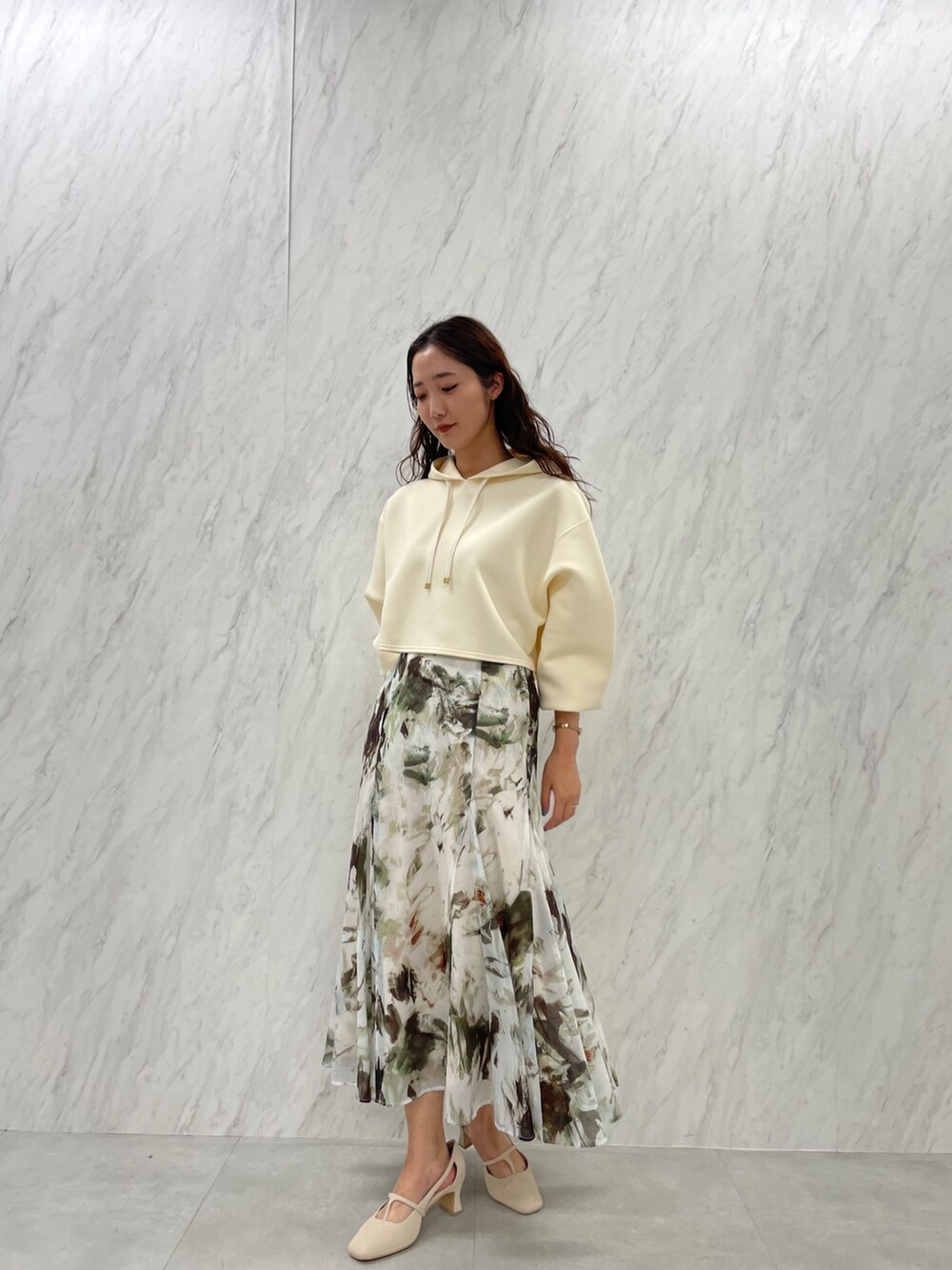 ホワイト系のパンプス、ベージュ系のスカート、ホワイト系のパーカーを着用したレディースの冬コーディネートの3枚目の写真