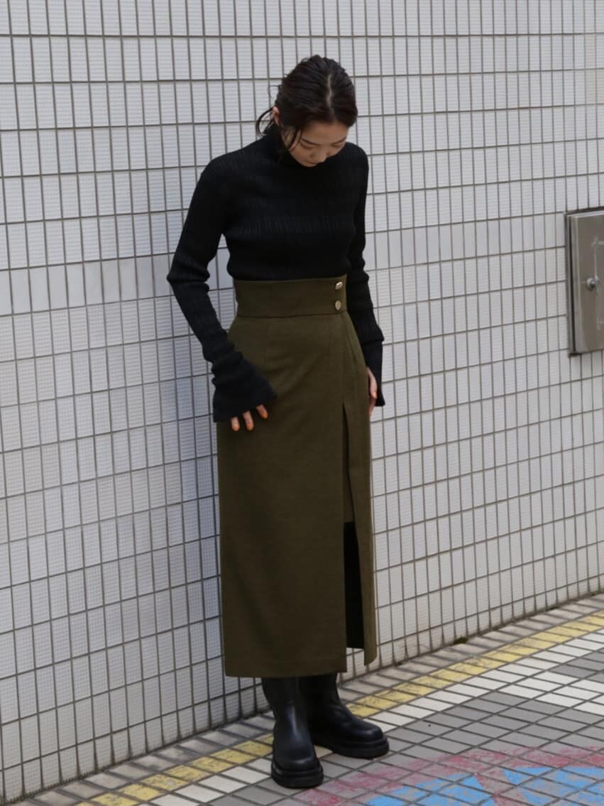 ベージュ系のスカート、ブラック系のニット/セーター、ブラック系のブーツを着用したレディースの夏コーディネートの2枚目の写真
