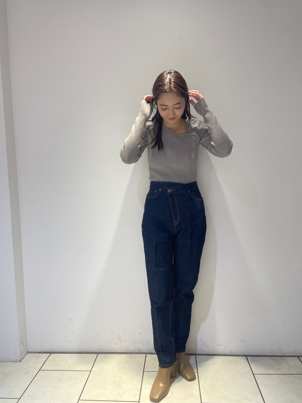 ホワイト系のノーカラーコート、グレー系のニット/セーター、ブルー系のデニムパンツを着用したレディースの秋コーディネートの6枚目の写真