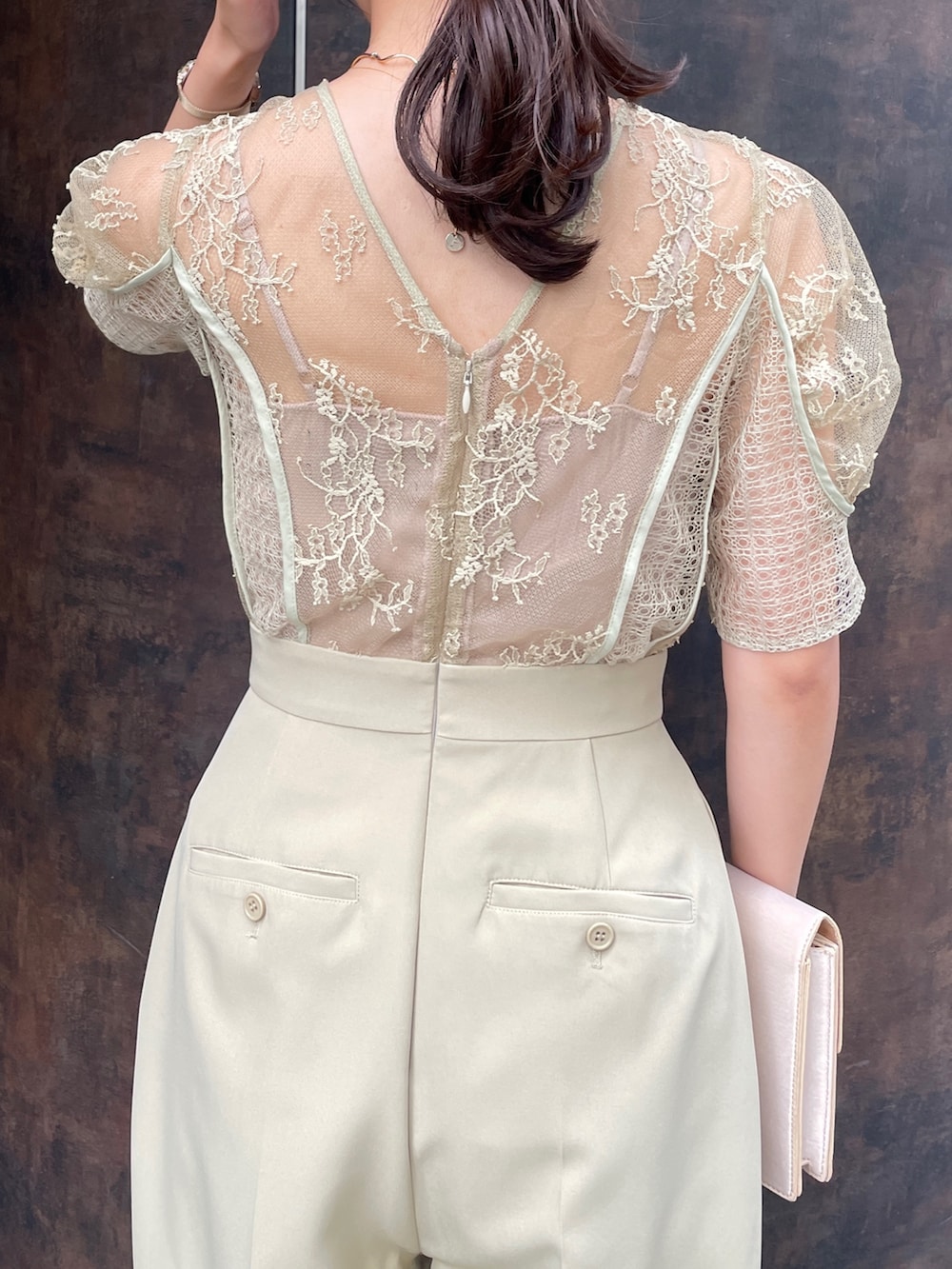 グリーン系のパンツドレス、ベージュ系のクラッチバッグ、ベージュ系のパンプスを着用したレディースの冬コーディネートの10枚目の写真