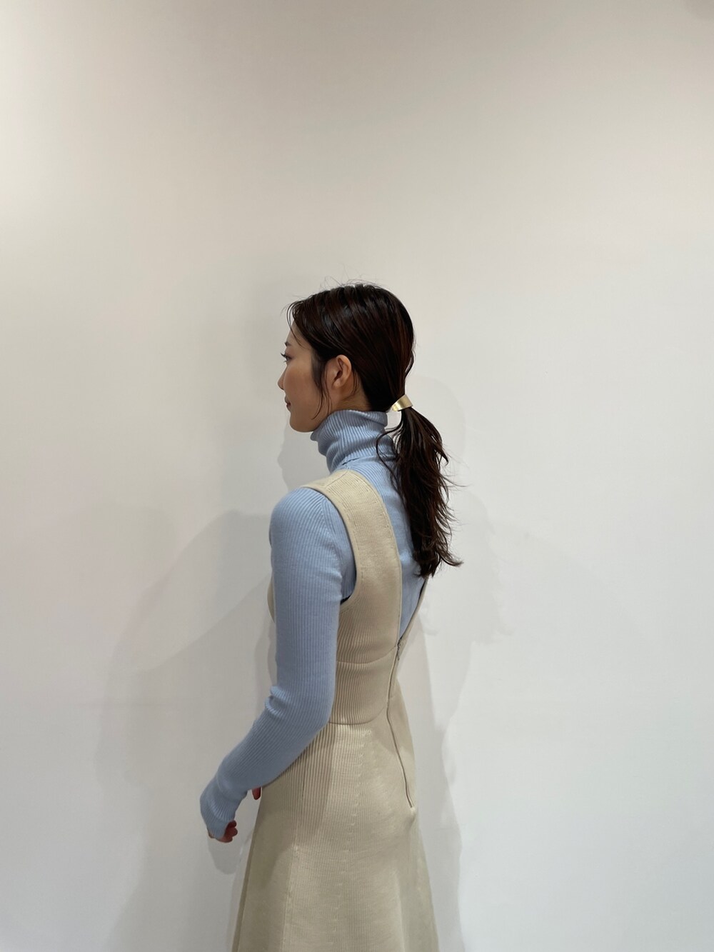 ブルー系のニット/セーター、ホワイト系のジャンパースカート、ホワイト系のブーツを着用したレディースの夏コーディネートの7枚目の写真
