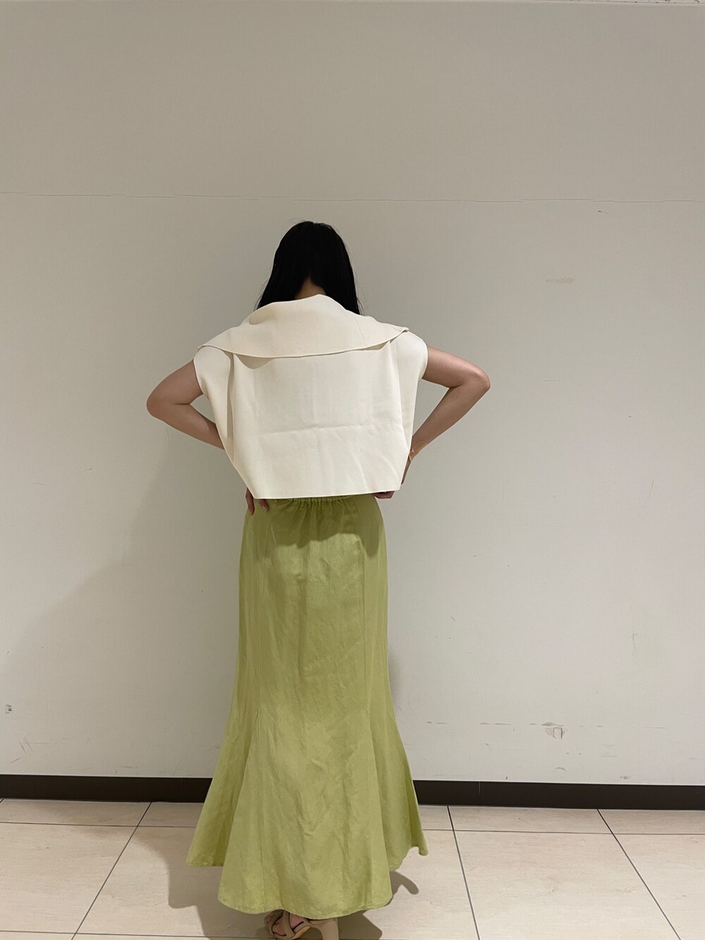 ホワイト系のニット/セーター、ベージュ系のサンダル、グリーン系のスカートを着用したレディースの春コーディネートの7枚目の写真