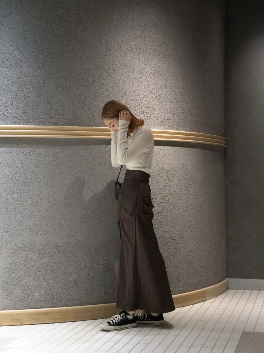 ブラック系のショルダーバッグ、ブラウン系のスカート、ホワイト系のニット/セーターを着用したレディースの秋コーディネートの3枚目の写真